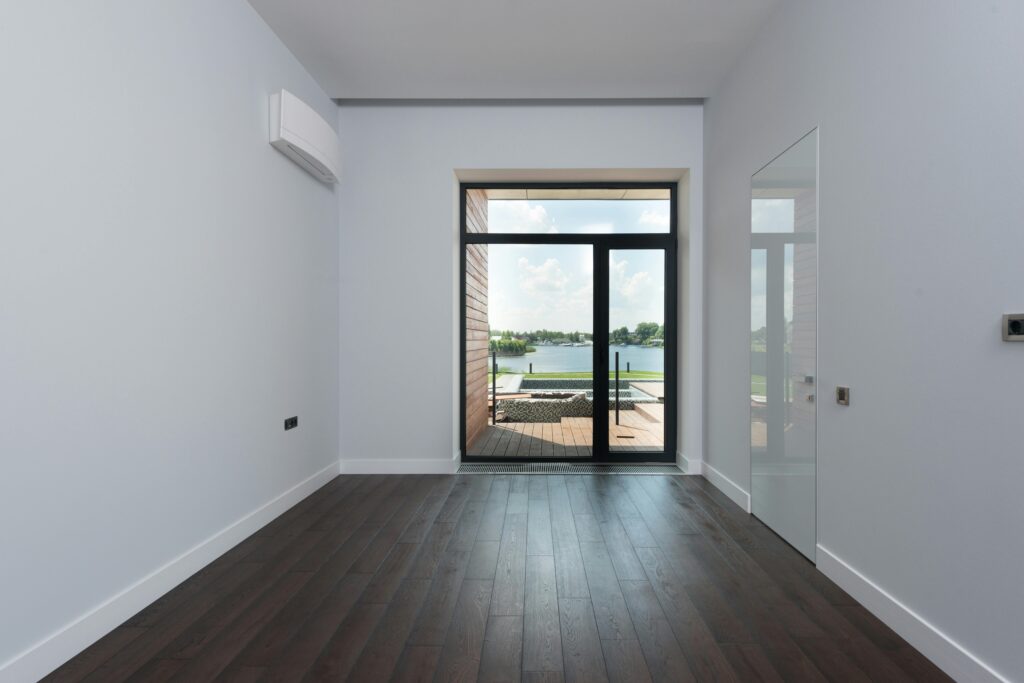 Spacious minimalist room with a stunning lake view through large glass doors.